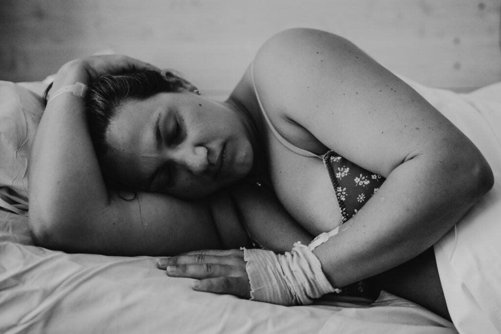 Village For Mama A woman laying in bed with a bandage on her hand.